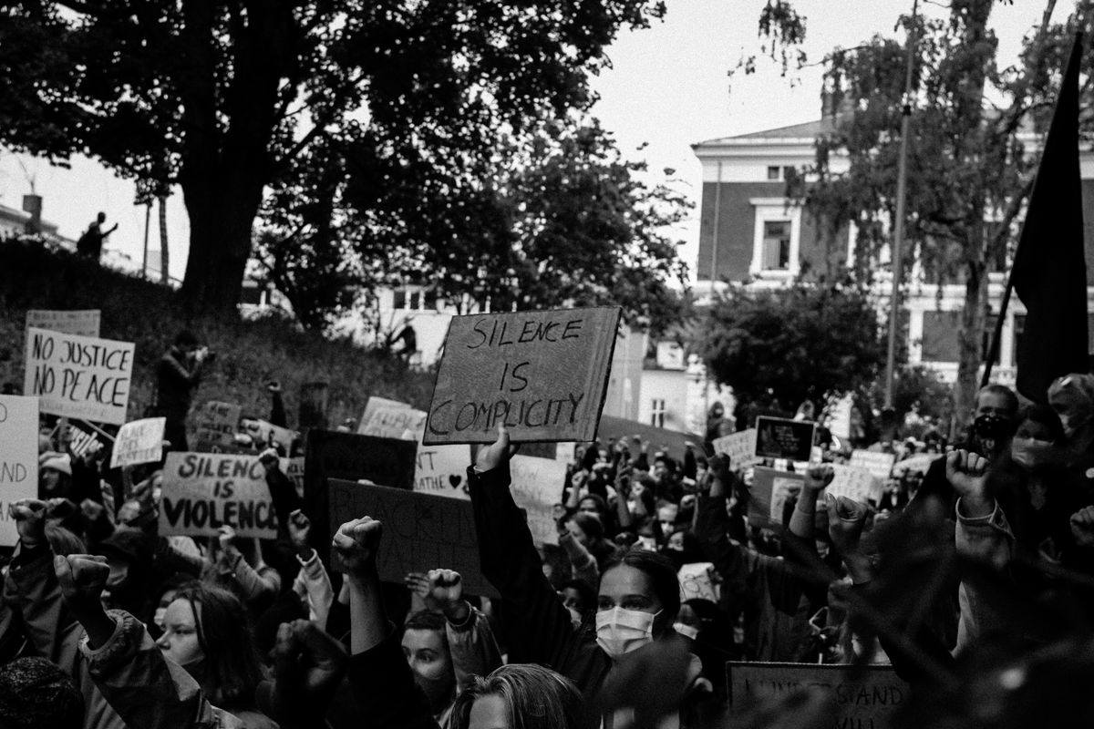 A powerful black and white image of a protest rally with signs demanding justice and peace.
