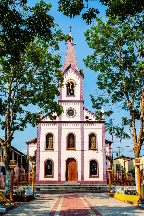 Free A vibrant historic church facade in the heart of Oriximiná, Brazil, surrounded by trees. Stock Photo