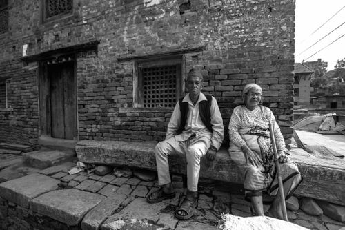 Free A senior couple sitting outside a brick building in Katmandu, Nepal. Stock Photo