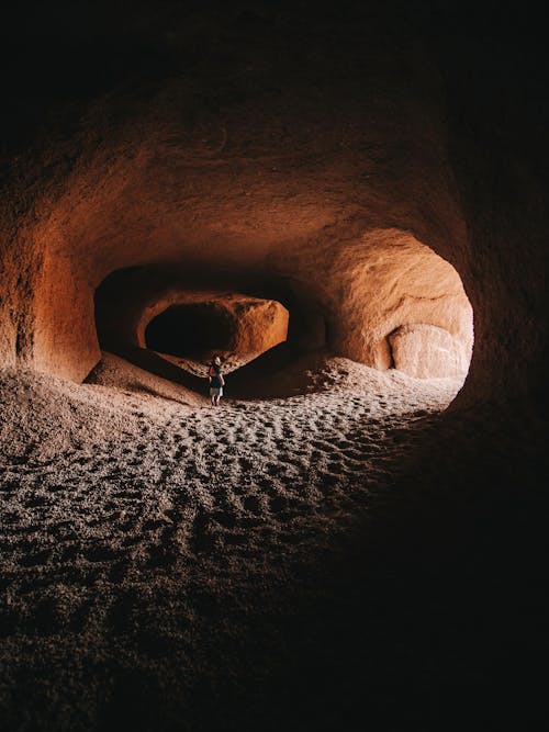 Person in rocky sandy cave with rough terrain