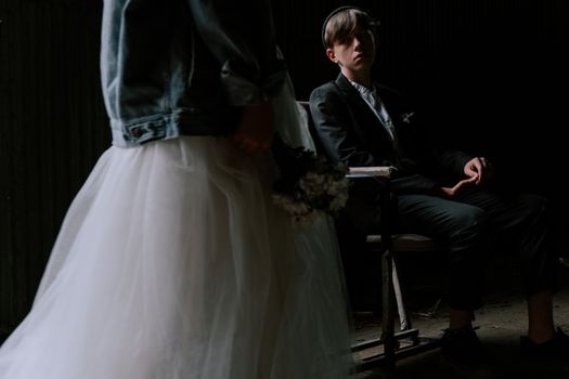 An artistic wedding photo with a moody atmosphere, showcasing a bride in a denim jacket and groom in a suit.