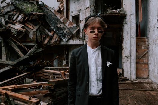 A young teen in stylish attire poses confidently in a derelict building setting.