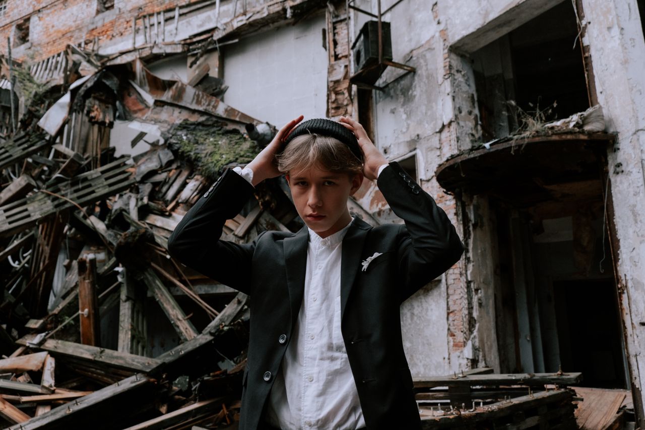 a young man poses confidently in a stylish outfit against a backdrop o