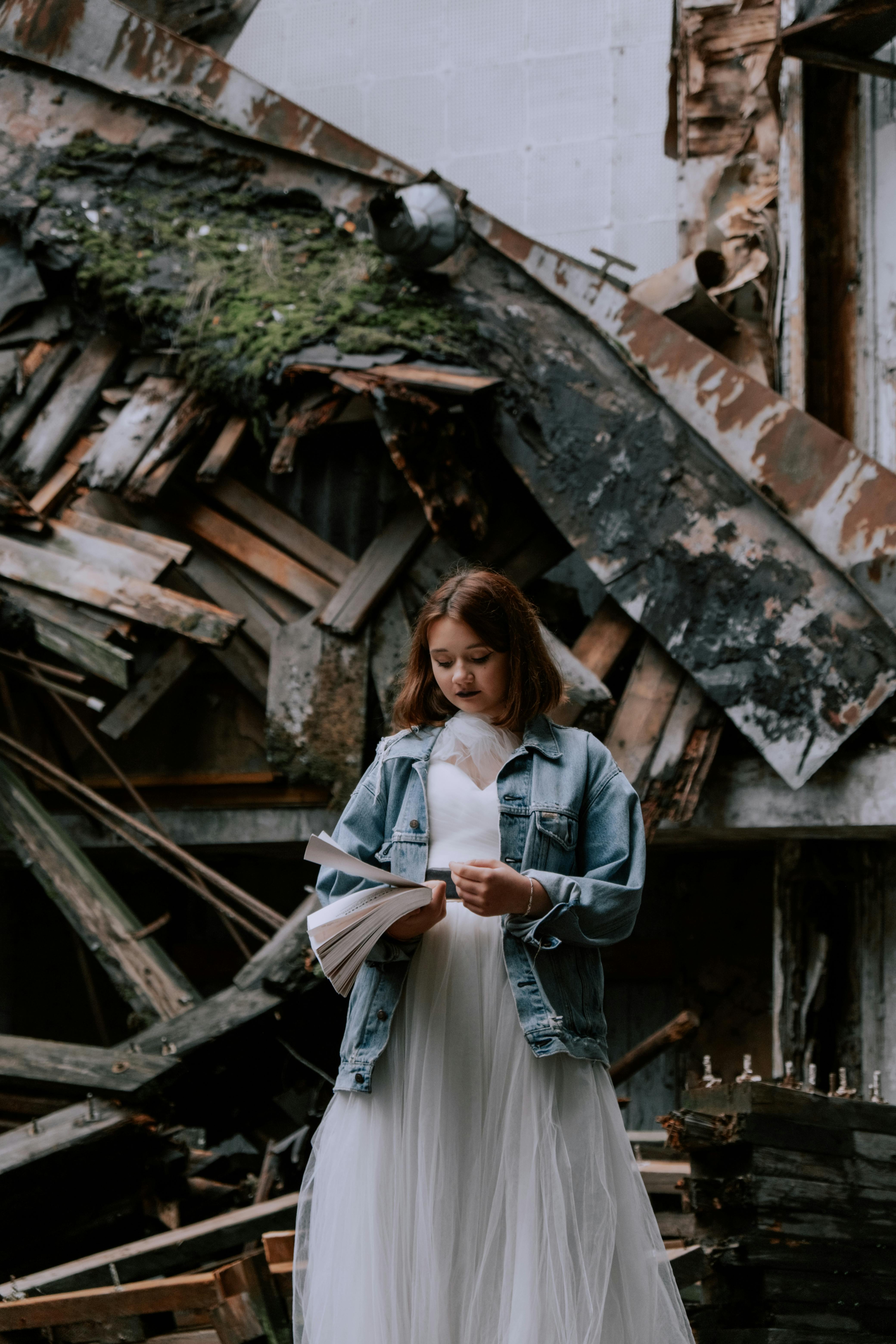 Bezpłatne Kobieta W Białej Sukni Z Długim Rękawem Stojącej Obok Brązowego Drewnianego Domu Zdjęcie z galerii