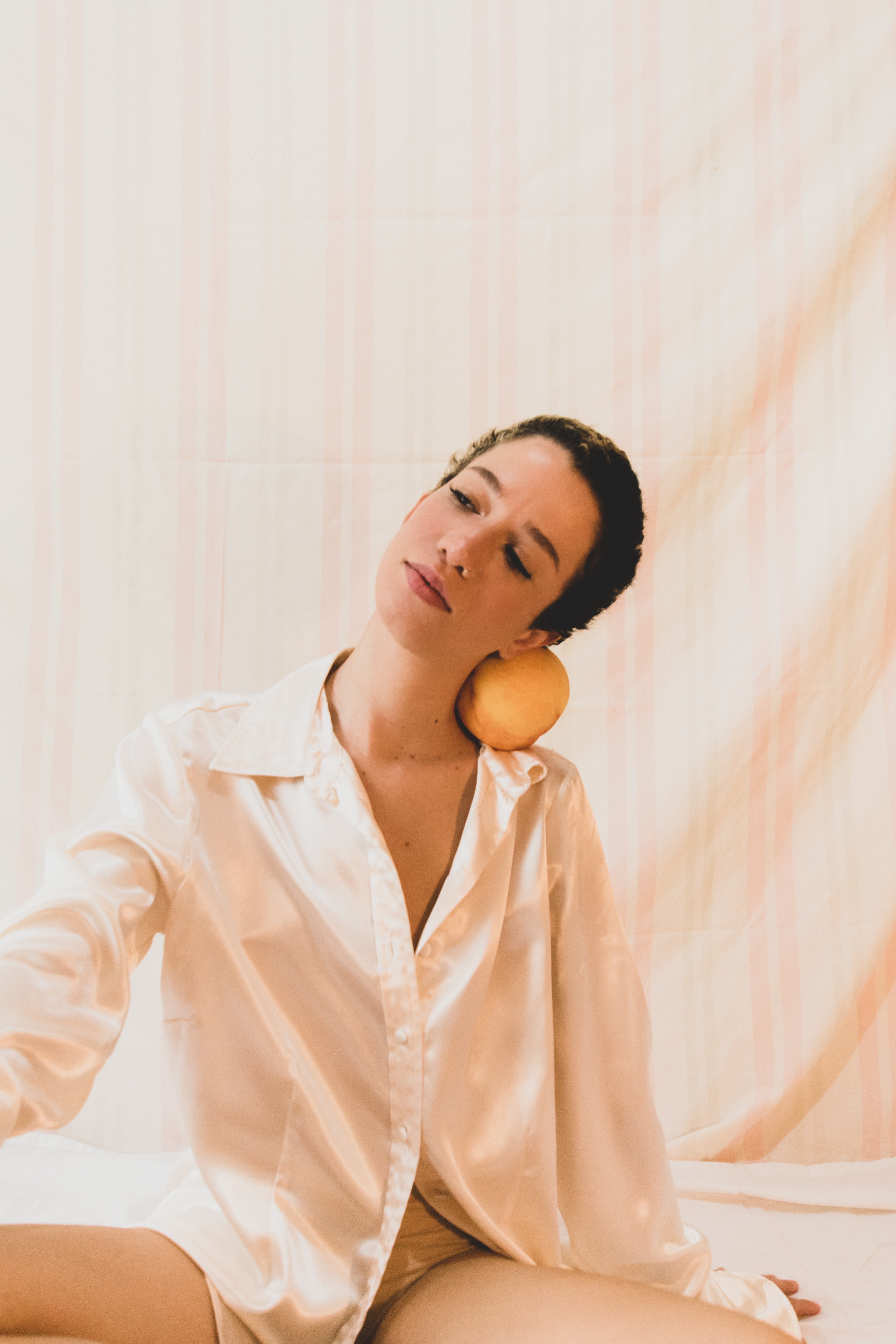 A serene indoor portrait of a woman in a white silk blouse with a neutral background.