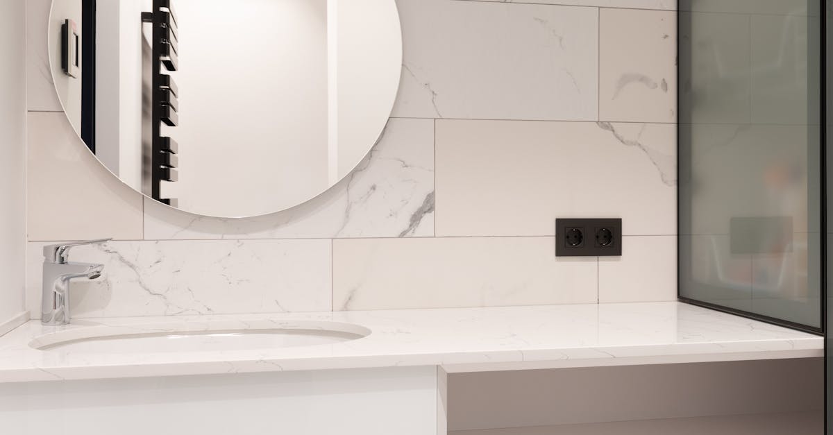 Interior of modern bathroom with marble tiled walls and round mirror over sink