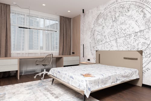 Free Modern room with wide bed under map on wall and long table with comfortable chair Stock Photo