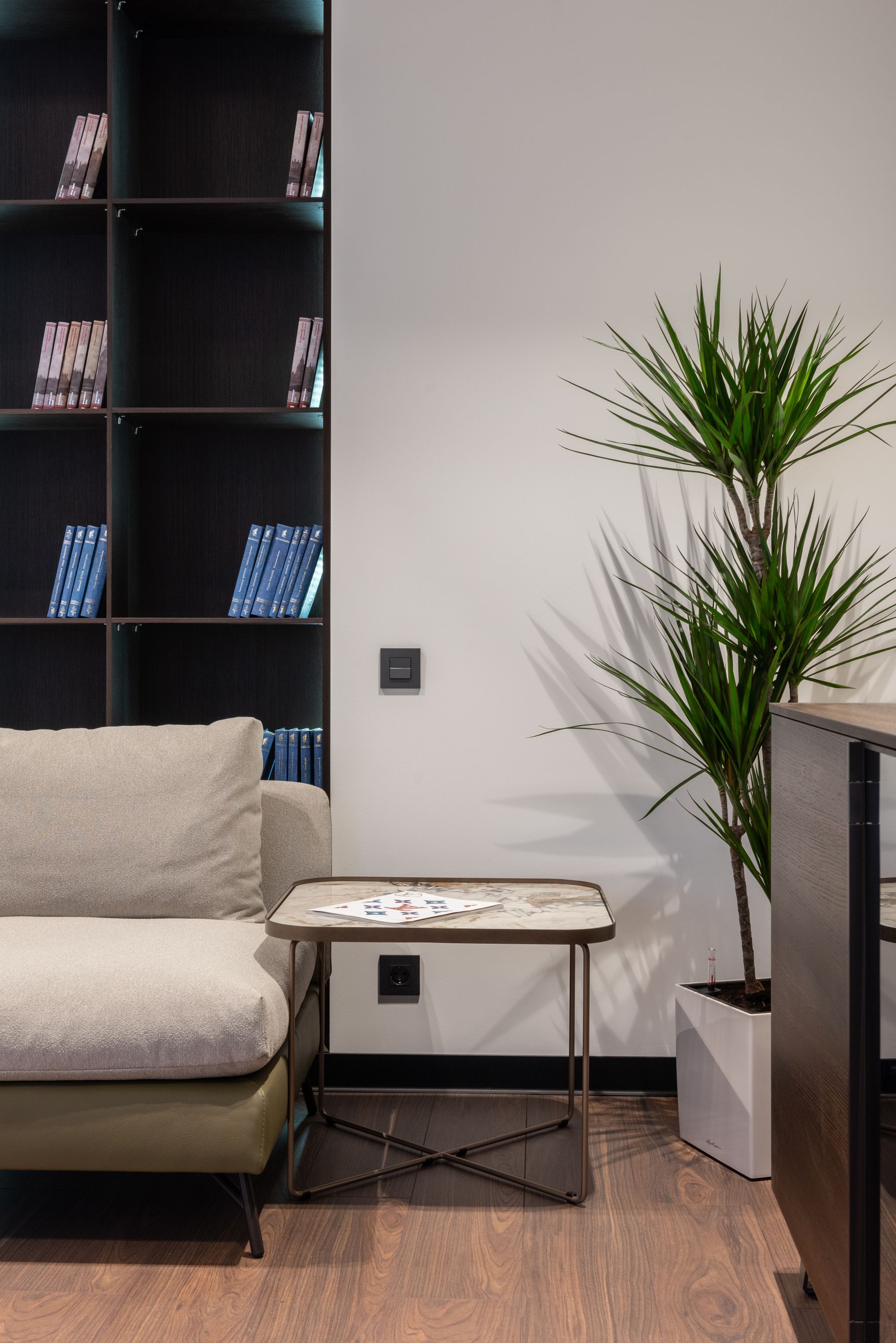 Compact side table positioned beside a contemporary sofa and shelving
