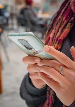A person holding a smartphone outdoors in a bustling street in Barcelona.