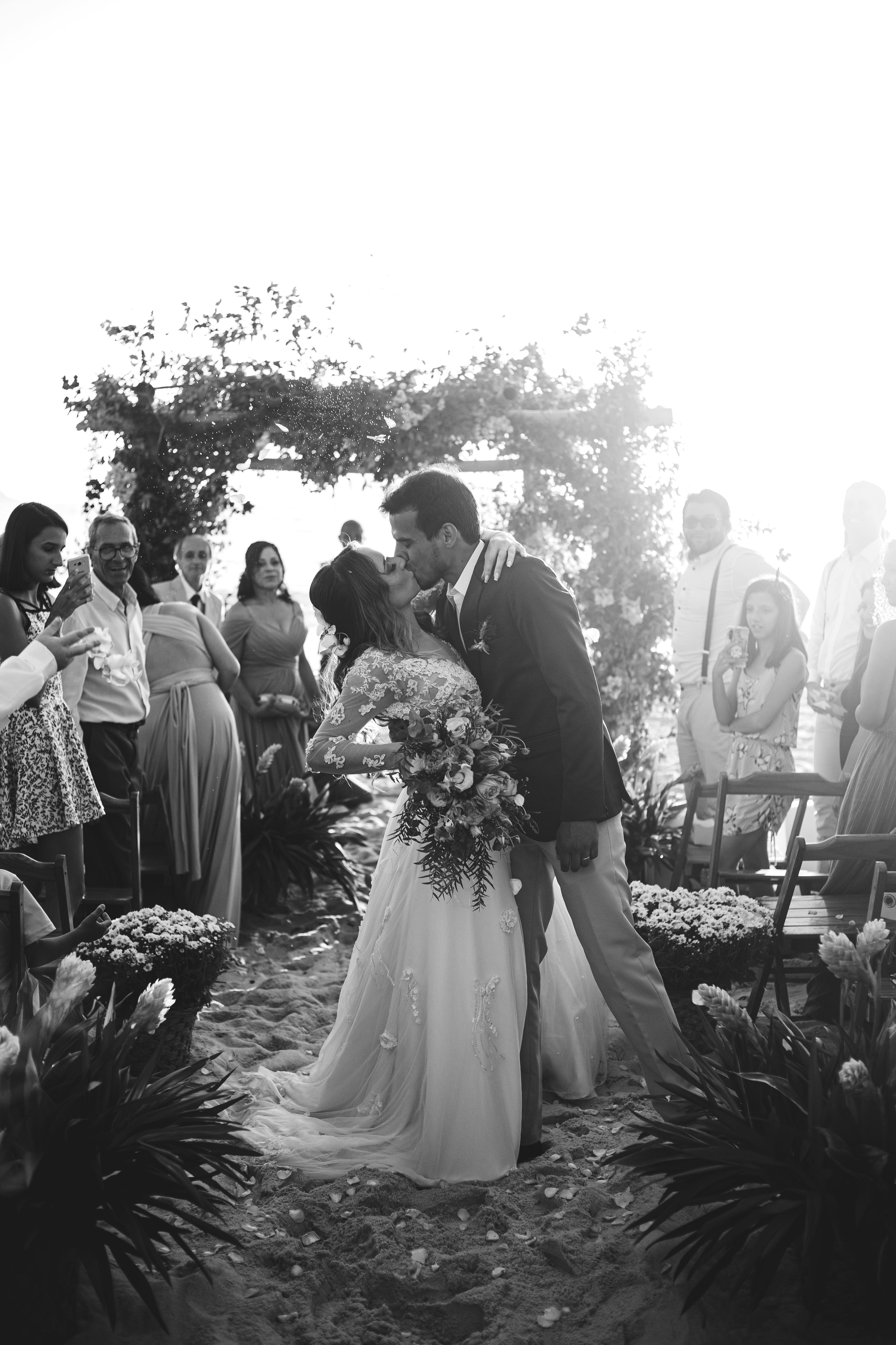 Captured moment of a couple kissing during their beach wedding ceremony.