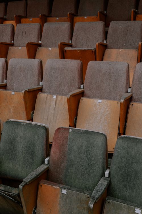 Free A weathered and dusty row of wooden seats in an empty theater, showcasing industrial decay. Stock Photo