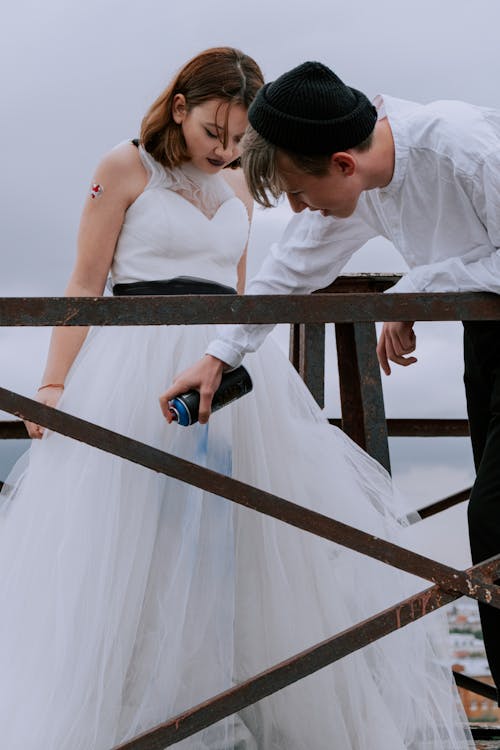 Woman in White Sleeveless Dress Holding Black Bottle