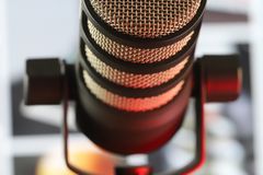 Contemporary studio recording condenser microphone on black stand placed in room with bright framed paintings on blurred background in studio