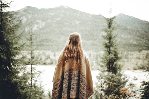 Miễn phí Người Phụ Nữ Mặc Poncho Nâu đối Mặt Với Núi Ảnh lưu trữ