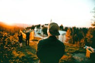 戴帽子的人在山顶森林的覆盖下欣赏宁静的日落，捕捉到户外静谧的场景