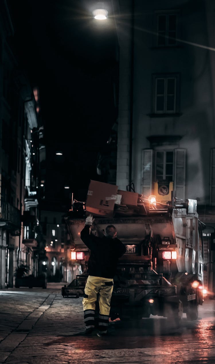 Unrecognizable Man Collecting Garbage At Night