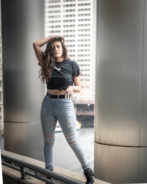 Woman in black sports bra and blue denim jeans standing on stairs