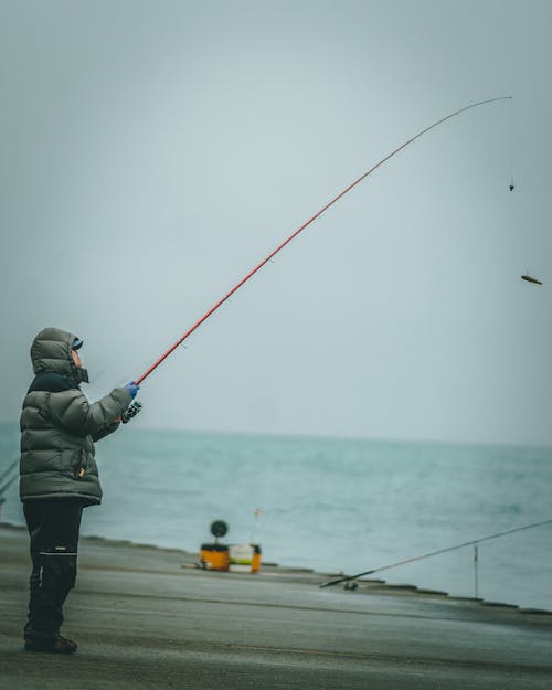 Man Wearing Hoodie Jacket Fishing on the Harbor