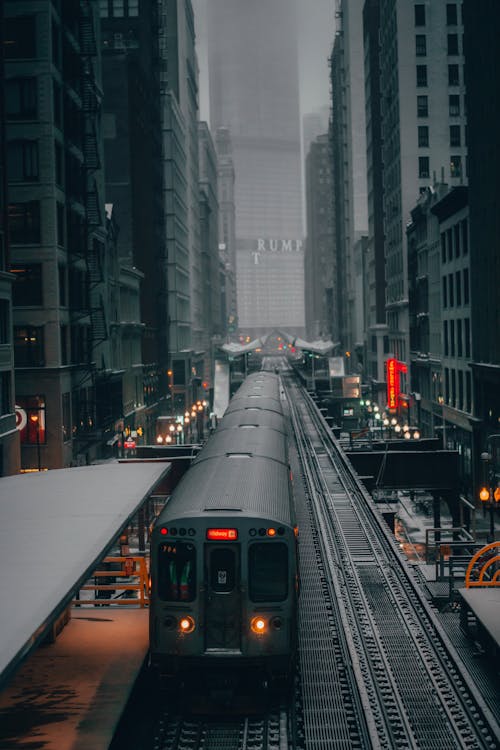 Gray Train on the Track Between City Buildings