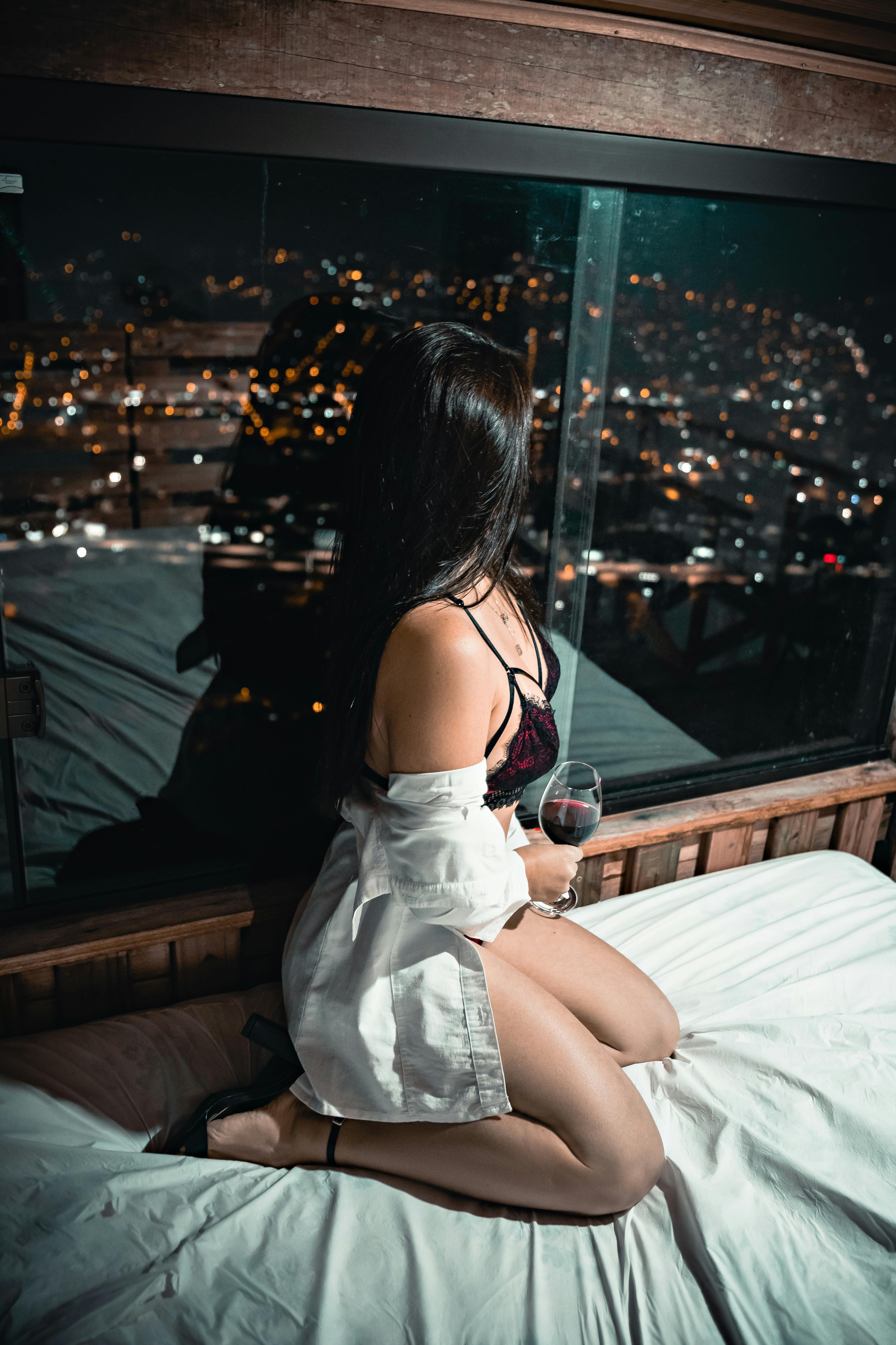 overhead view of sexy brunette woman in red bra lying on bed at home and  touching hair, Stock image