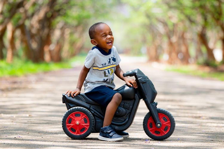 Cute Kid Riding A Toy Scooter