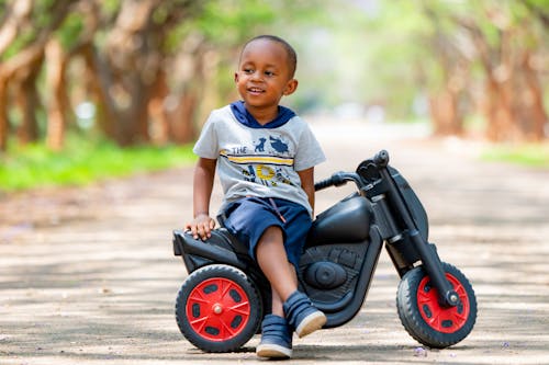 Free Happy Kid Sitting on a Black Toy Scooter Stock Photo