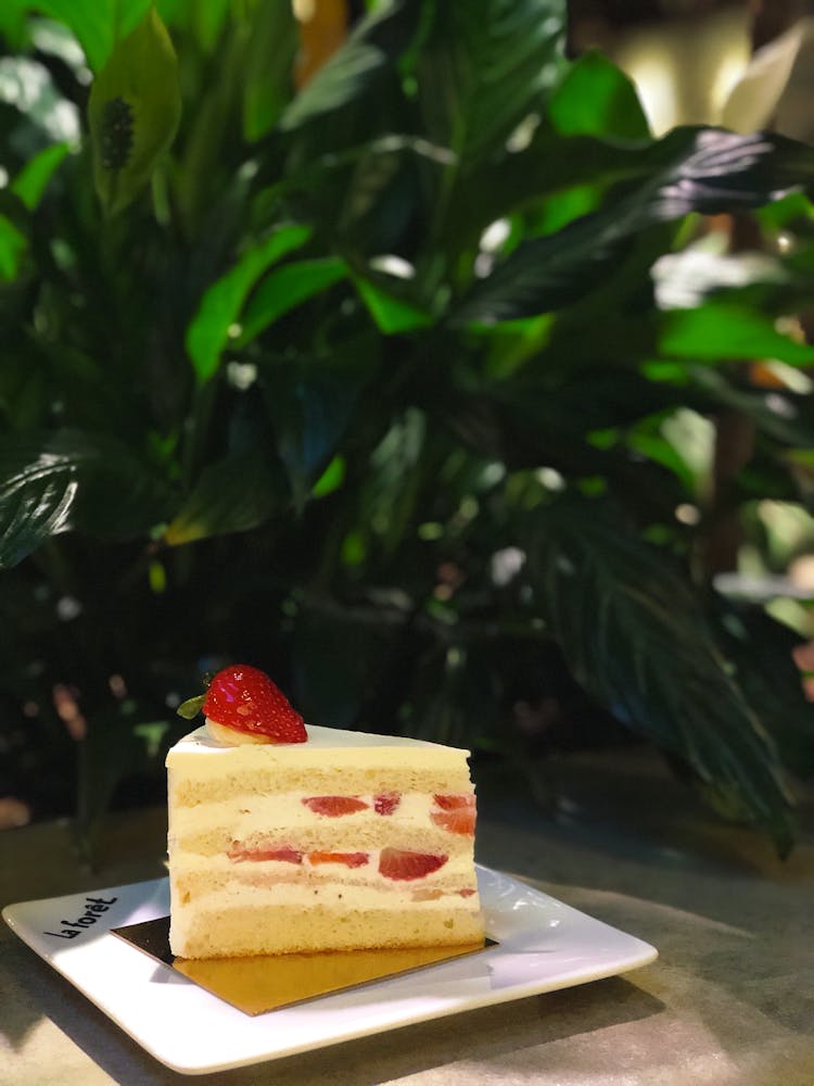 Piece Of Cake With Strawberries On White Plate Under Green Plate