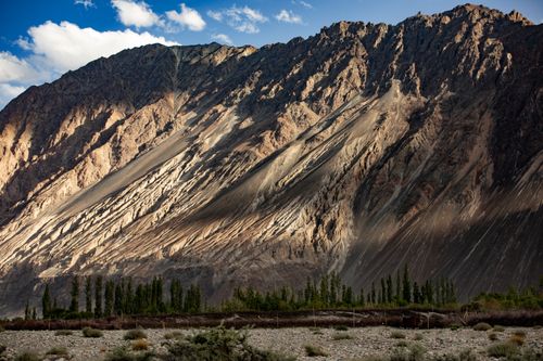 Free Stunning view of a majestic mountain range under a clear blue sky, showcasing rugged terrain and lush foreground. Stock Photo