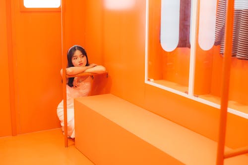 Young Woman in White Dress Sitting in Orange Interior