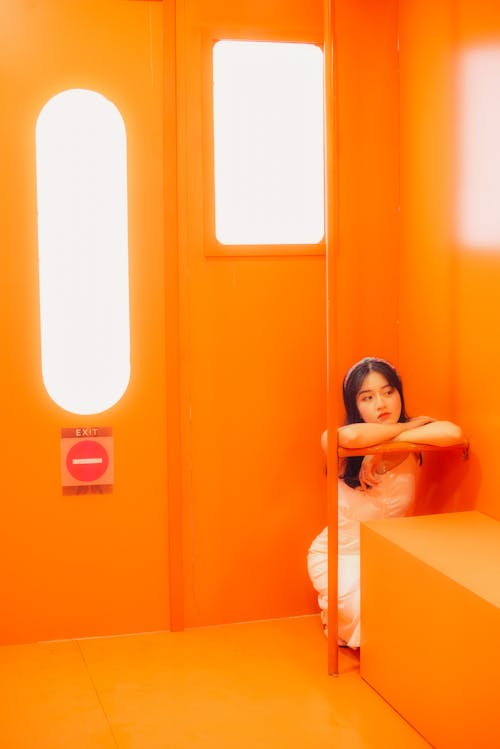 Young Woman in White Dress Sitting in Orange Room
