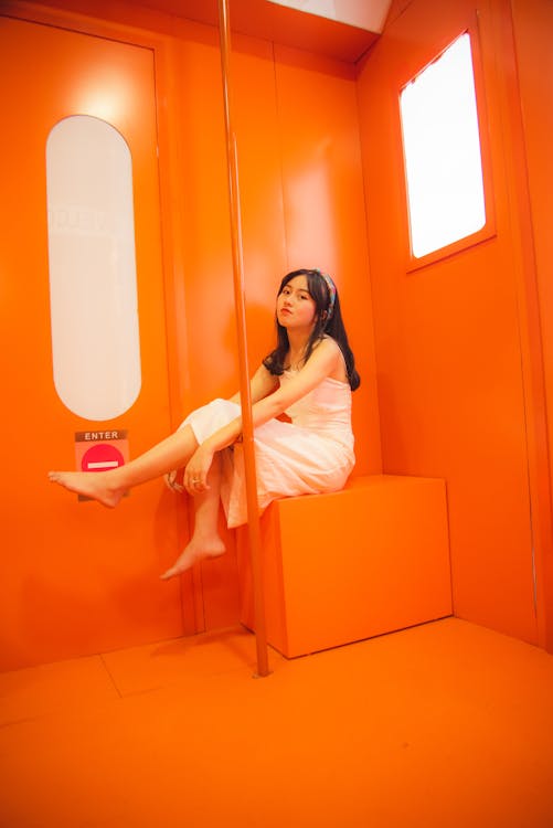 Young Woman Barefoot Sitting on Orange Seat