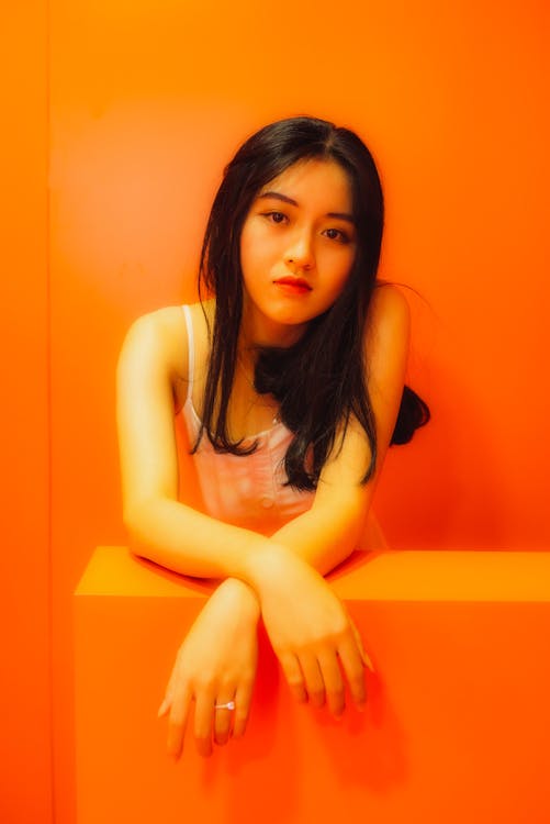 Woman in Orange Background Looking at the Camera 