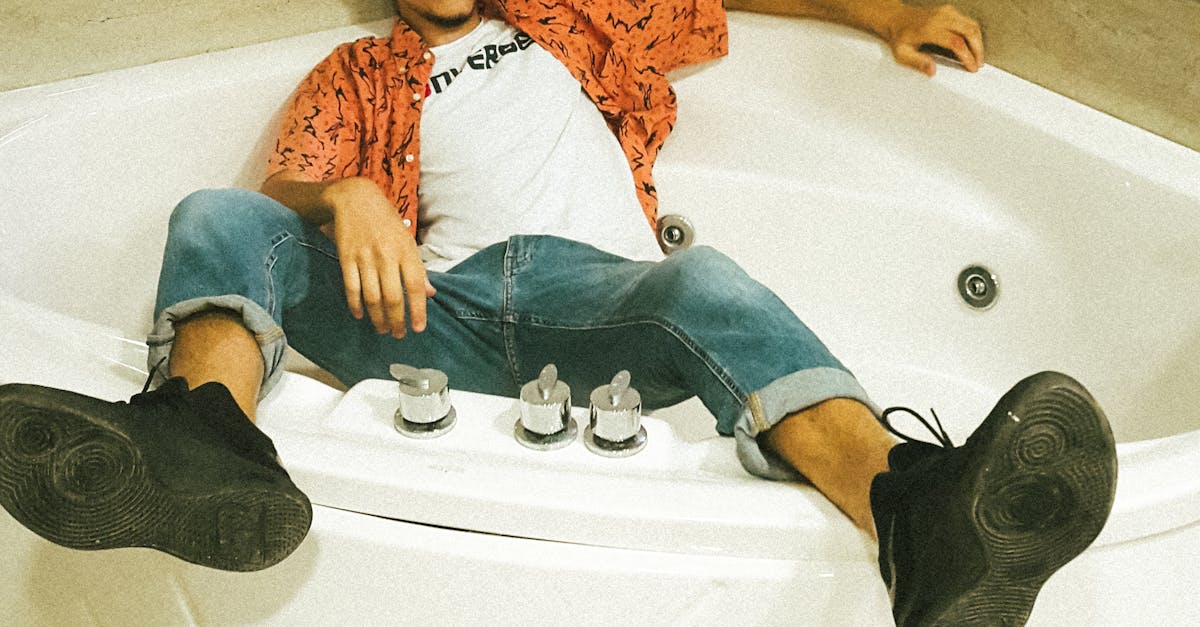 Young Man Sitting in Bathtub in Clothes
