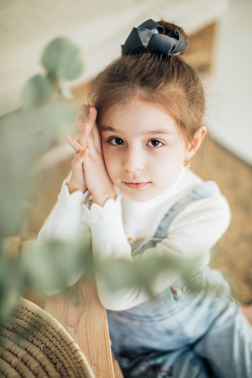 Free A pretty young girl indoors, looking at the camera with a gentle expression, wearing a casual outfit. Stock Photo