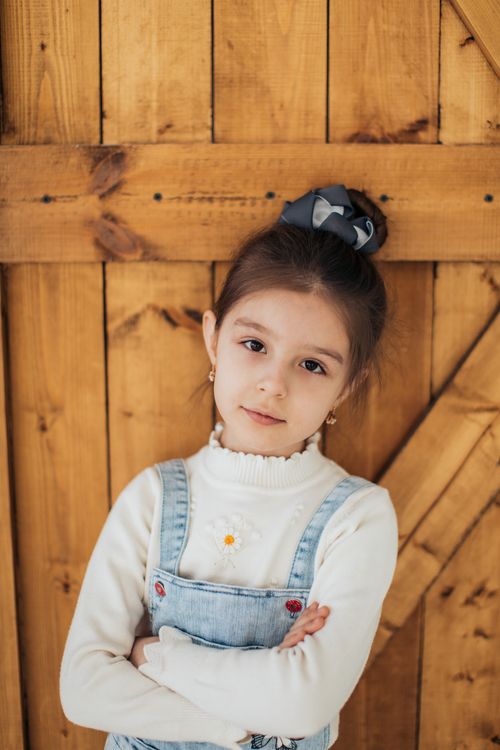 Free Cute young girl posing with crossed arms indoors, showcasing style and confidence. Stock Photo
