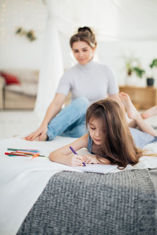 Free A mother and daughter spending creative quality time drawing together indoors. Stock Photo