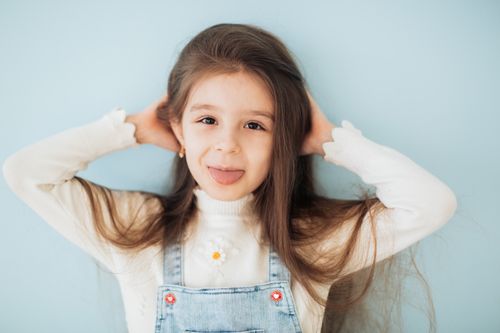 Free Cute child playfully sticking out tongue against a blue background. Stock Photo
