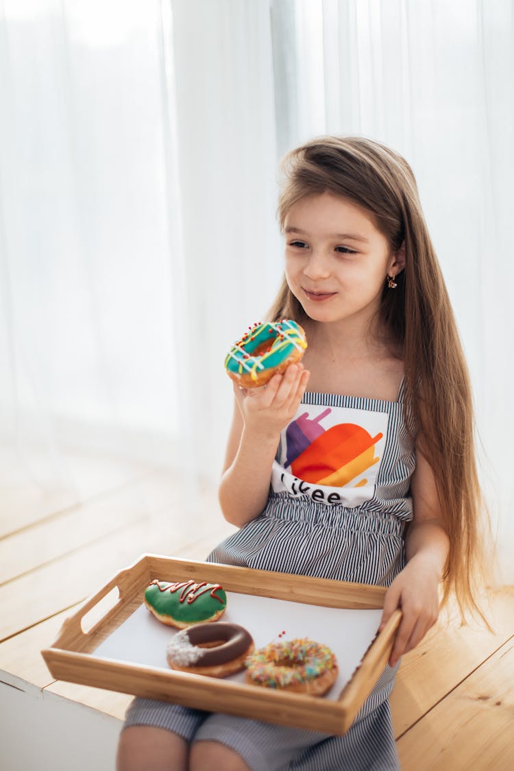 Photograph Of A Kid Eating Donuts