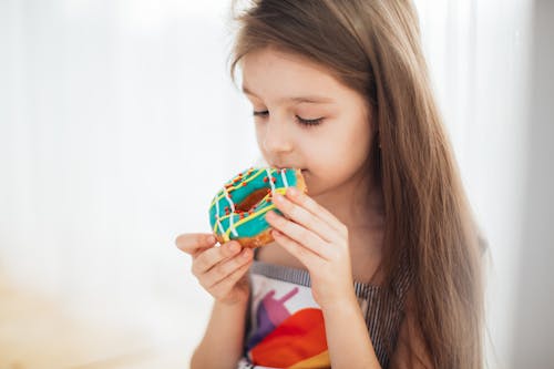 Photograph of a Girl Eating a Donut with 