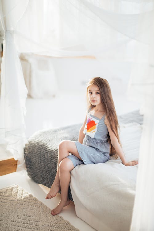 Photo of a Girl Sitting on a Bed