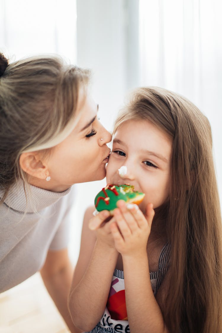 Woman Kissing A Girl Eating A Doughnut