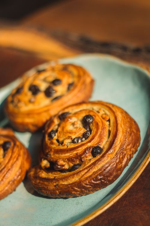 Free Close-up shot of freshly baked pain aux raisins on a rustic plate, perfect for breakfast. Stock Photo
