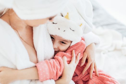 Close up of Mother and Daughter in Bathrobes Cuddling
