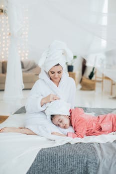 A mother and daughter enjoying a cozy moment in bathrobes on a bed, indoors.