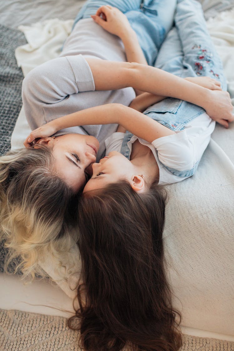 Photo Of Mother And Daughter Cuddling On A Bed And Hair Hanging Down