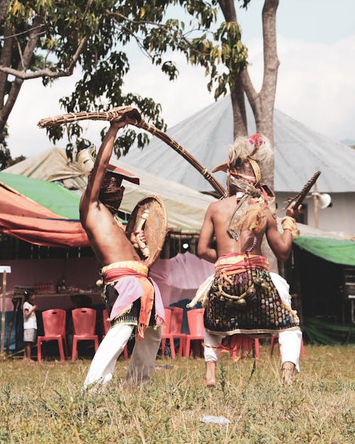 Men in Traditional Costumes Dancing on a Field 
