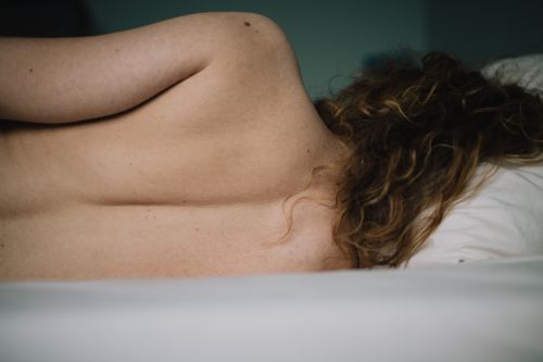 Free A serene and artistic pose of a woman lying on a bed, emphasizing natural beauty. Stock Photo