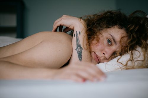 Free A close-up of a tattooed woman lying down, exuding calm and intimacy indoors. Stock Photo