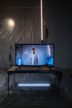 Child on a TV screen in a dimly lit studio with plastic drapes, cool lighting, and modern equipment.