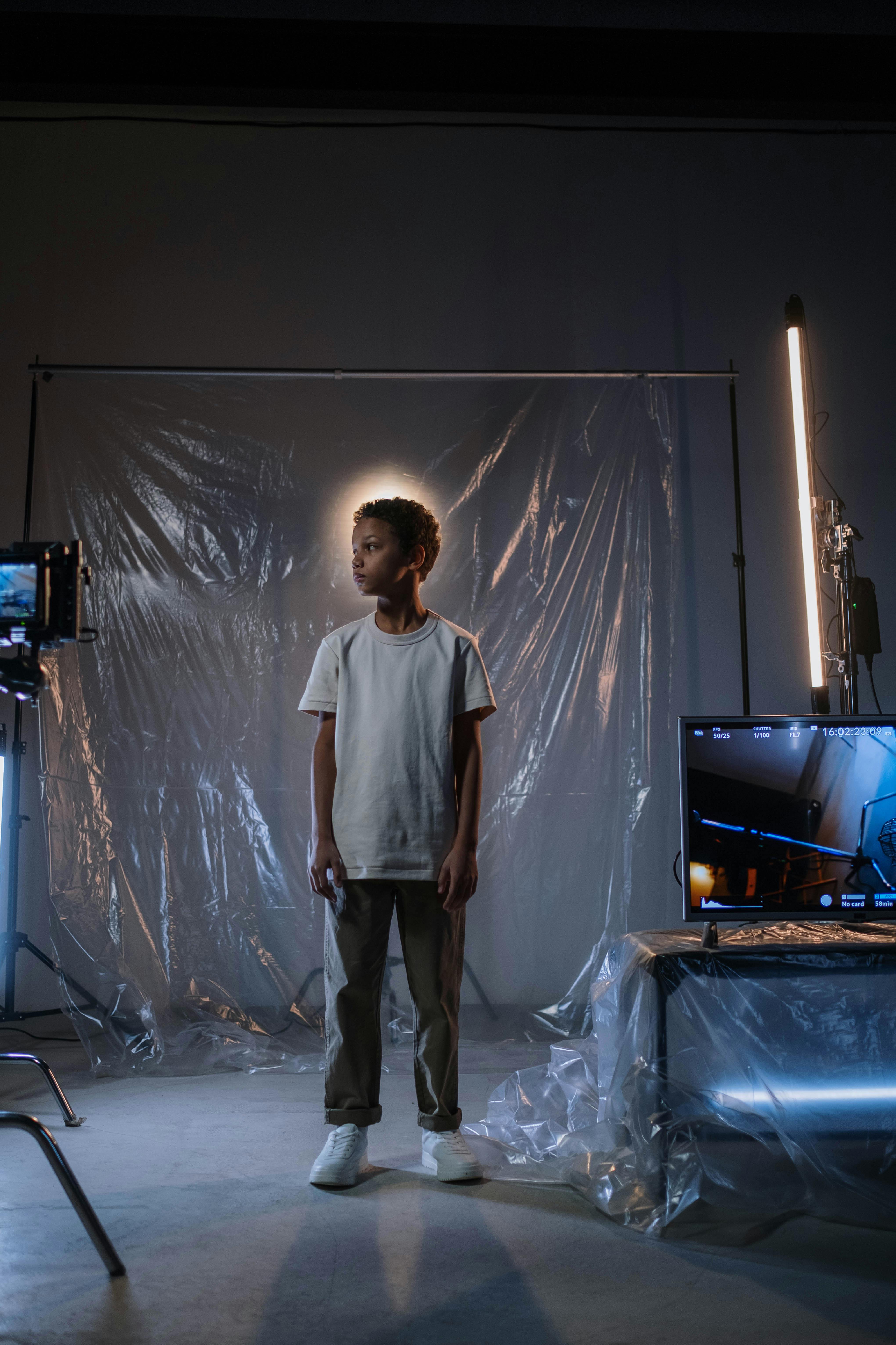 boy un white shirt standing near tv monitor